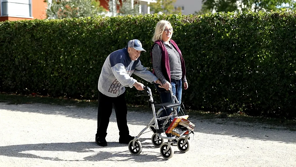 Ein Senior und die Pflegekraft seiner Wahl gehen spazieren