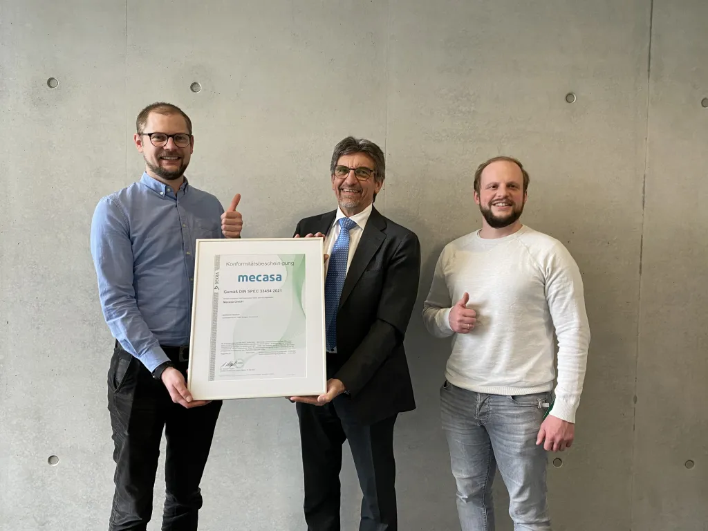 Mecasa erhält als erster Pflegevermittler die Zertifizierung nach DIN SPEC 33454. Das Zertifikat wird überreicht von Dr. Gerhard Nagel, Geschäftsfeldleiter DEKRA Certification